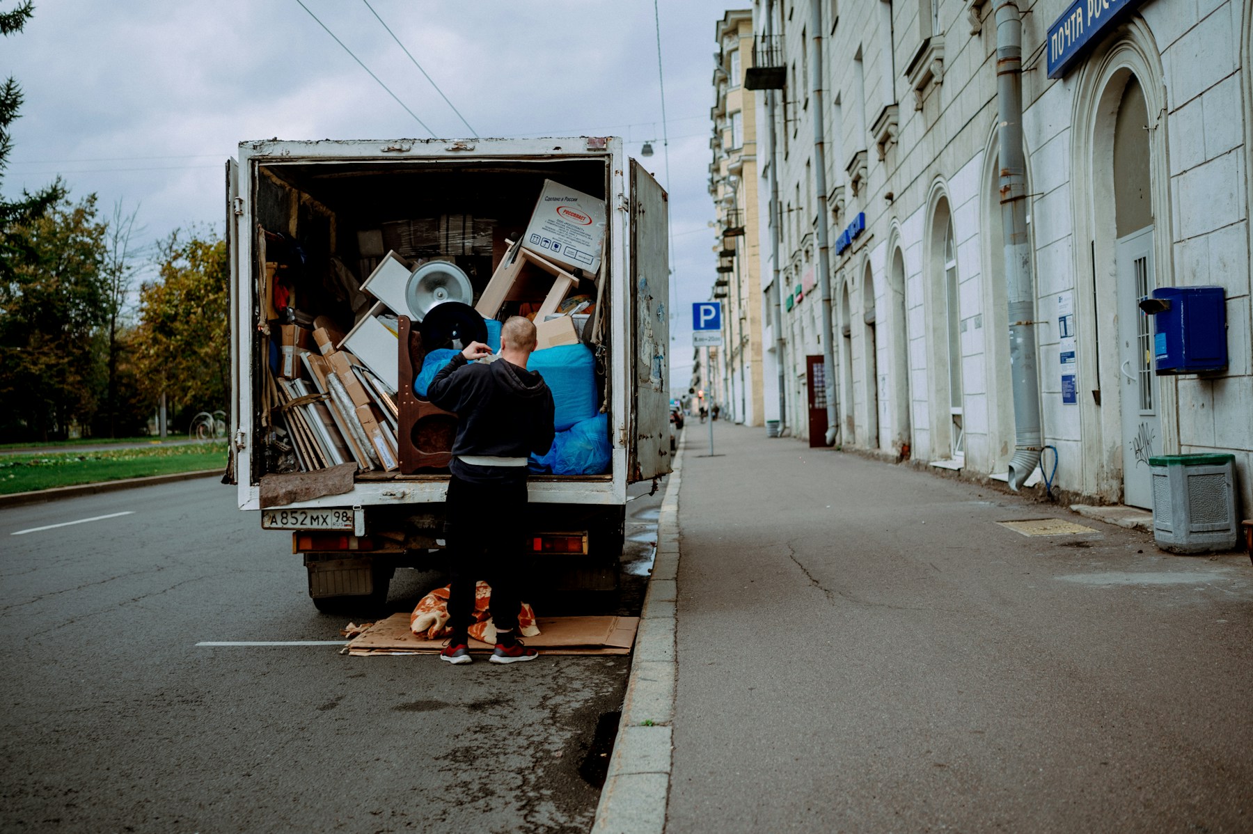 Worker loading bulky household items into a hauling truck
