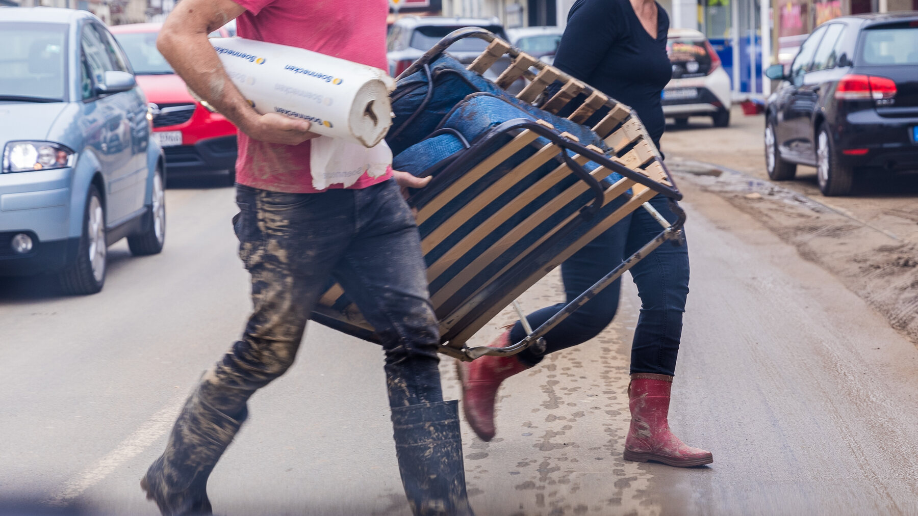 Two people carrying damaged furniture during a property cleanout